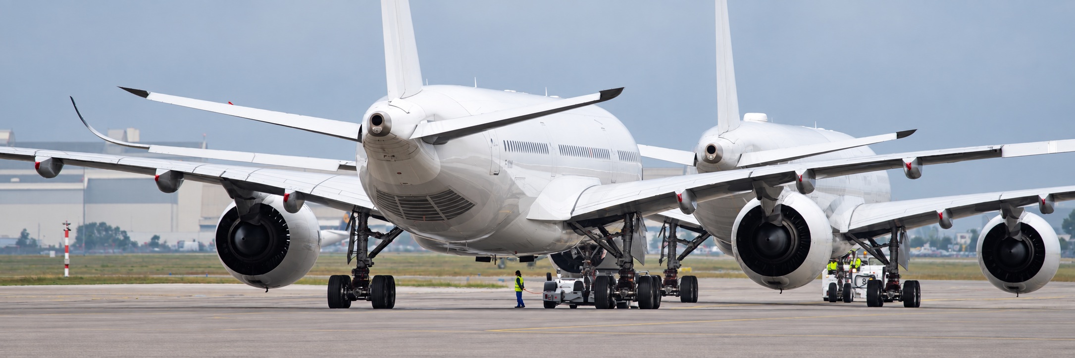 Aircraft with ground crew and towing vehicles on the apron